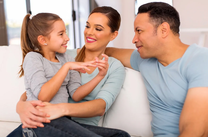 A woman and two men sitting on top of a couch.